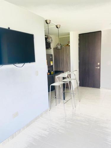 ein Wohnzimmer mit Stühlen und einem Flachbildfernseher an der Wand in der Unterkunft Apartamento Ibague in Ibagué
