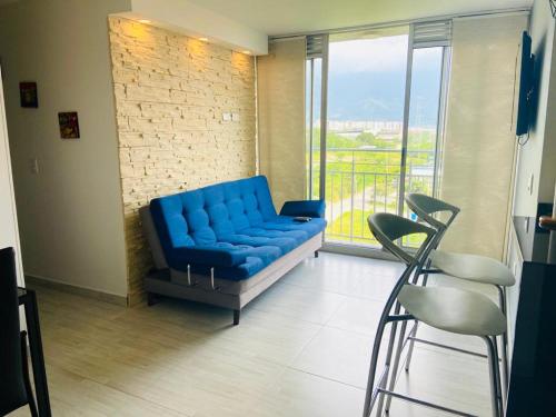 ein blaues Sofa in einem Zimmer mit einem großen Fenster in der Unterkunft Apartamento Ibague in Ibagué