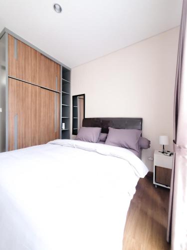 1 dormitorio con 1 cama blanca grande con almohadas moradas en RT House Cozy Homestay 2BR Podomoro Golf View en Taladjurg-udik