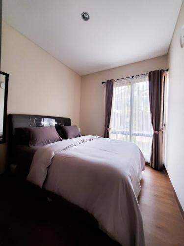 Taladjurg-udikにあるRT House Cozy Homestay 2BR Podomoro Golf Viewのベッドルーム(大型ベッド1台、窓付)