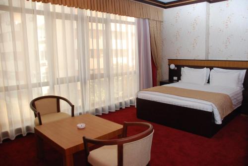Habitación de hotel con cama, mesa y ventana en Alp Inn Hotel, en Baku