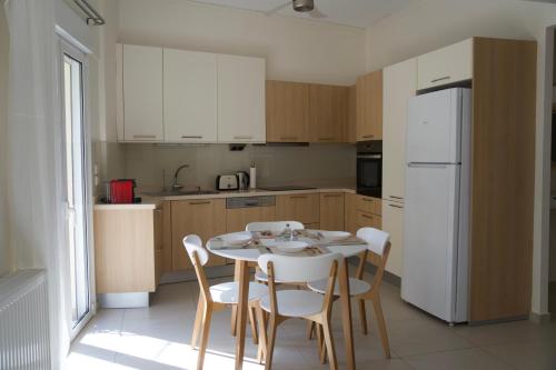 een keuken met een tafel en stoelen en een witte koelkast bij Cristina‘s Place in Heraklion