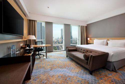 une chambre d'hôtel avec un lit et un canapé dans l'établissement JS Luwansa Hotel & Convention Center, à Jakarta