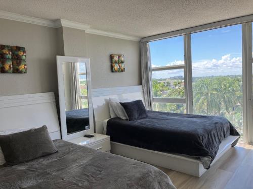 a bedroom with two beds and a large window at Oceanview on SAND located in Ocean Manor Resort Fort Lauderdale Beach 2 bed 2 bath spacious corner unit partial ocean view in Fort Lauderdale