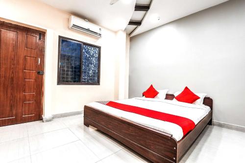een slaapkamer met een bed met rode kussens bij OYO Flagship Sathya Inn in Warangal