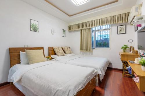 a bedroom with two beds and a desk and a window at West Lake Hefang Street Metro Exit B&B in Hangzhou