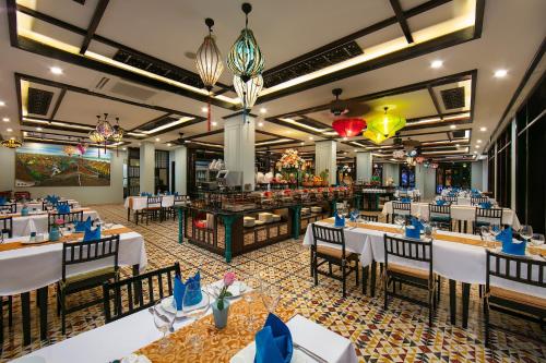 a dining room with white tables and chairs at La Charm Hoi An Hotel & Spa in Hoi An
