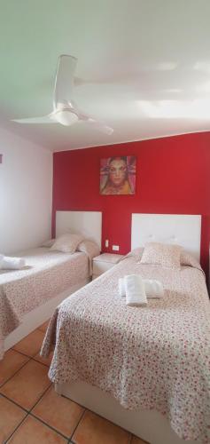 1 dormitorio con 2 camas y pared roja en Apartamentos JANESKA, en Tías