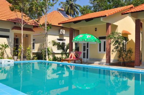 a person sitting under an umbrella next to a swimming pool at Đức Anh Bungalow in Phu Quoc