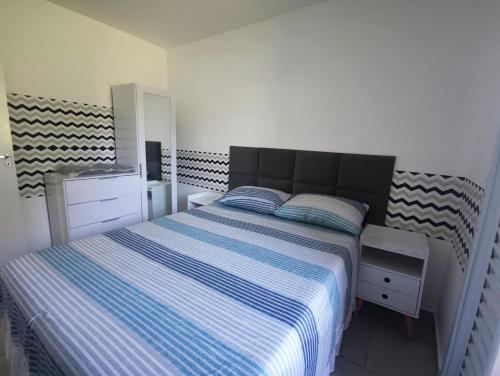 um quarto com uma cama com um cobertor listrado azul e branco em Apartamento próximo ao shopping em Poços de Caldas