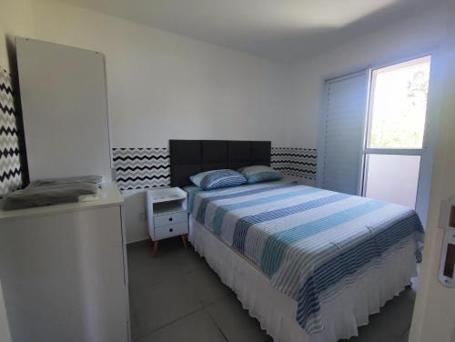 a white bedroom with a bed and a window at Apartamento próximo ao shopping in Poços de Caldas