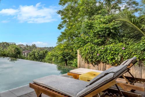 a chair sitting next to a body of water at Bisma Eight - CHSE Certified in Ubud