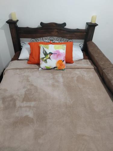 a bed with orange and white pillows on it at Gran Hotel Desamparados in Desamparados