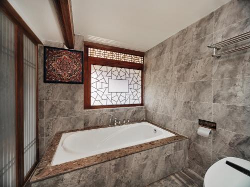 a bathroom with a bath tub and a window at 夕露小榭古城南门店 Xilu Xiaoxie Inn Old Town Lijiang in Lijiang