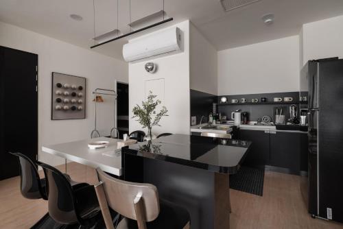 eine Küche mit einer schwarz-weißen Theke und Stühlen in der Unterkunft 双層公寓 Duplex Apt. in Tainan