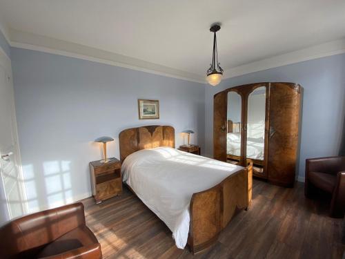 1 dormitorio con 1 cama grande y espejo en Vintage holiday apartment on the 1st floor of an elegant mansion - Coutances, en Coutances