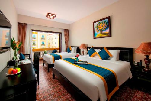 a hotel room with two beds and a television at La Charm Hoi An Hotel & Spa in Hoi An