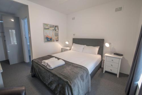 a bedroom with a large white bed and a night stand at Bermagui Motor Inn in Bermagui