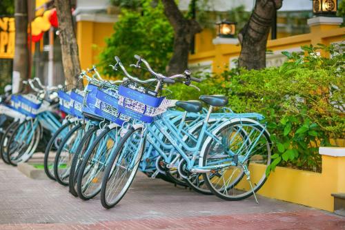 a row of blue bikes parked on a sidewalk at La Charm Hoi An Hotel & Spa in Hoi An