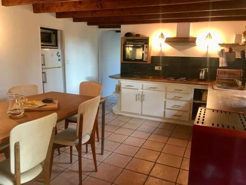 une cuisine avec une table et des chaises dans une cuisine dans l'établissement Maison chaleureuse et calme, à Panazol