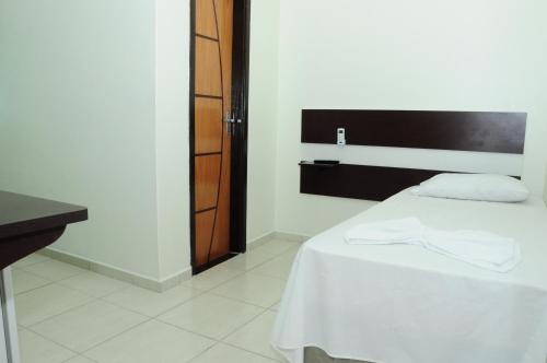 a bedroom with a white bed with a black headboard at Eder Hotel in Cacoal