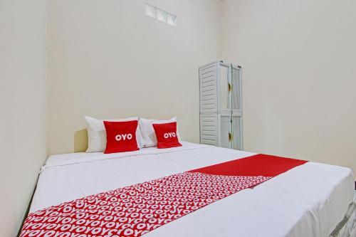 a bedroom with a bed with two red pillows at OYO Life 93034 Ayri Home in Salatiga