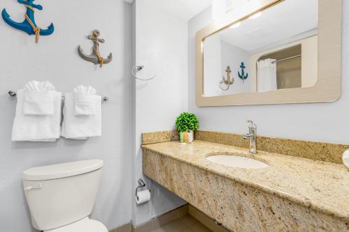 W łazience znajduje się umywalka, toaleta i lustro. w obiekcie Romantic Oceanfront Studio Escape w Perfect View 1212 w mieście Myrtle Beach