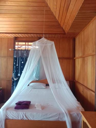 a bedroom with a bed with a net on it at Lestari Cottages in Kododa
