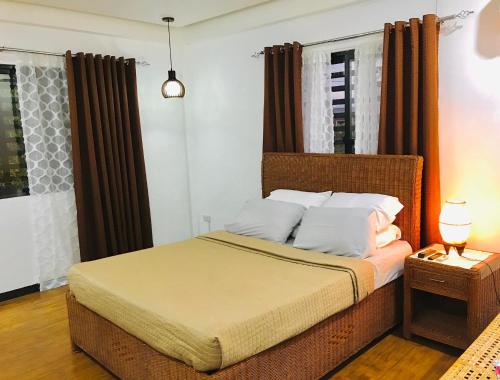 - une chambre avec un grand lit et des rideaux bruns dans l'établissement G Apartment - Home in Kabankalan City, à Kabankalan