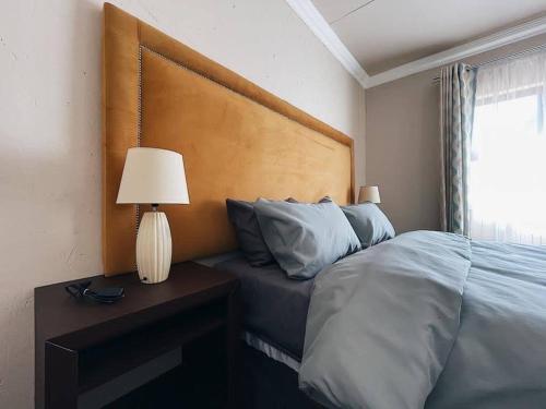 1 dormitorio con 1 cama y 1 mesa con lámpara en Sekgome Resort, en Johannesburgo