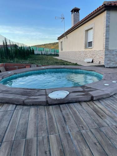 a swimming pool with a wooden deck and a house at Casa Rural La Costa in La Lapa
