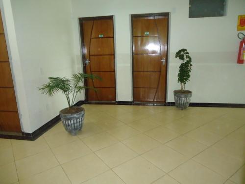 a hallway with two potted plants and two doors at Eder Hotel in Cacoal