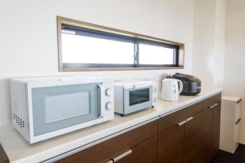 a kitchen counter with two microwaves and a microwave at ホテルコンドミニアム土花土花 in Onna