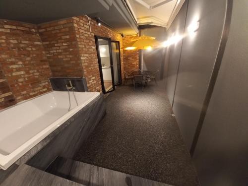 uma banheira num quarto com uma parede de tijolos em Adena Hotel em Busan