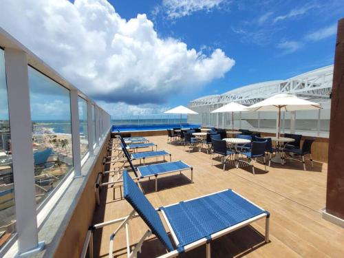a balcony with chairs and tables on a cruise ship at Lindo e novo apto com vista para o mar de Pituba c/garagem in Salvador