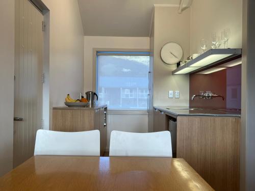 una cucina con tavolo e due sedie bianche di Waterscape Apartment ad Akaroa