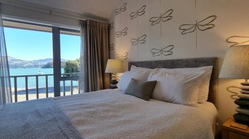 Dormitorio con cama y vistas al agua en Waterscape Apartment en Akaroa