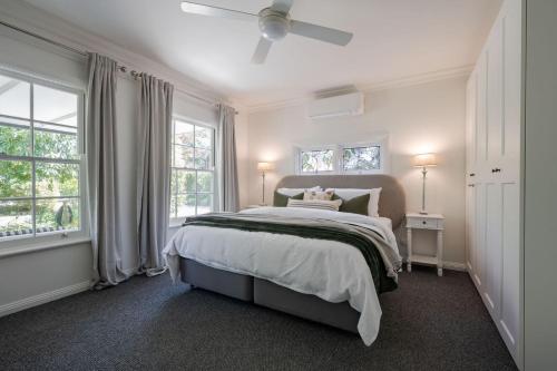 a bedroom with a large bed and two windows at Golden Pine Retreat in Bright