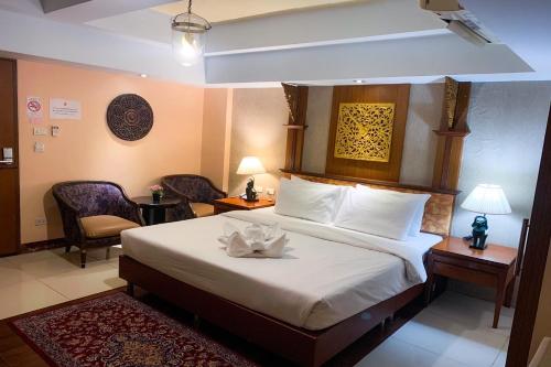 Habitación de hotel con 1 cama y 2 sillas en Kim Hotel At Morleng en Bangkok