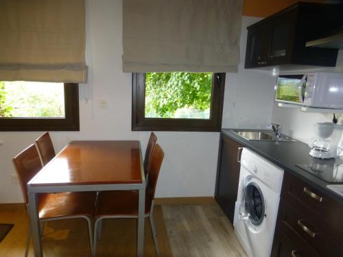 a kitchen with a table and a sink and a dishwasher at La Casina de Torra in Ribadesella