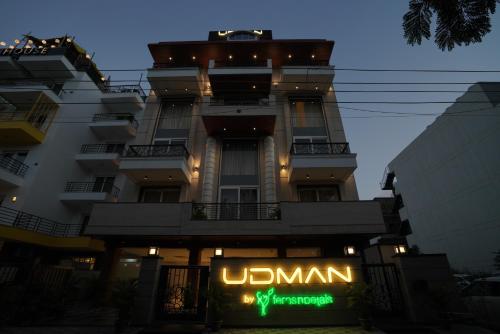 un edificio con una señal de neón delante de él en Udman Hotel Gurugram en Gurgaon