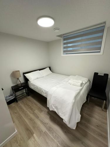 a bedroom with a white bed and a black chair at 2 Bedroom 2 Washrooms Brand New Beautiful & Cozy Suite in Calgary