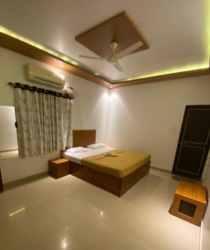Tarkarli Resort Ganpat Prasad في مالفان: غرفة بها سرير ومروحة سقف
