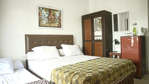 a bedroom with a bed and a refrigerator in it at Andelis Homestay in Yogyakarta