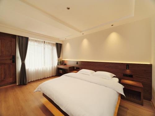 Un dormitorio con una gran cama blanca y una ventana en Xilu Xiaoxie Inn en Lijiang