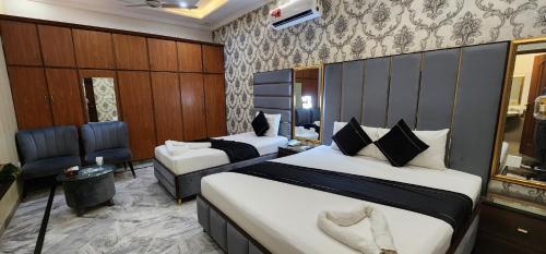 una habitación de hotel con 2 camas y una silla en Red Fort Hotel Gulberg en Lahore
