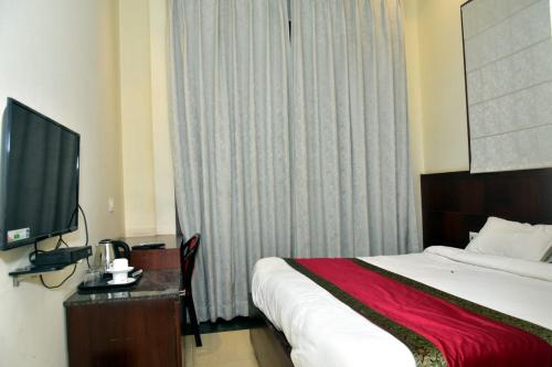 a hotel room with a bed and a flat screen tv at Hotel Atlantis in Varanasi