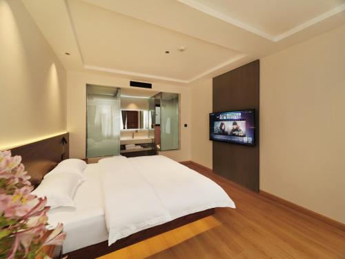 a bedroom with a white bed and a flat screen tv at 夕露小榭古城南门店 Xilu Xiaoxie Inn Old Town Lijiang in Lijiang