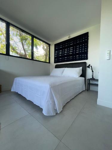 a bedroom with a white bed and two windows at Studio Gordy in Seminyak