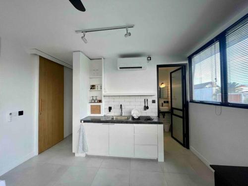 a kitchen with white cabinets and a large window at The Drupadi Apartments Studio Gordy in Seminyak
